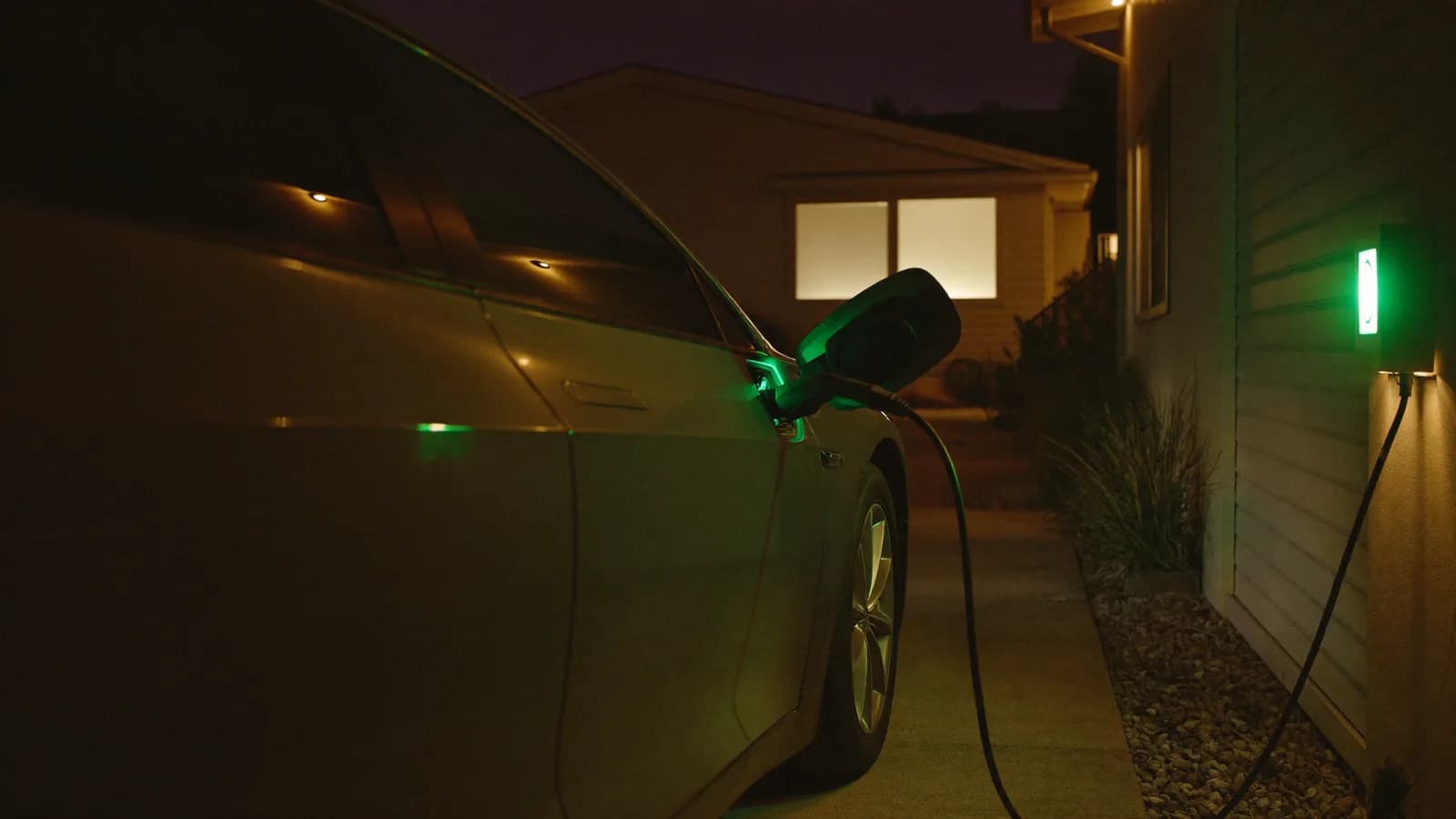 Electric car charging in a driveway at night