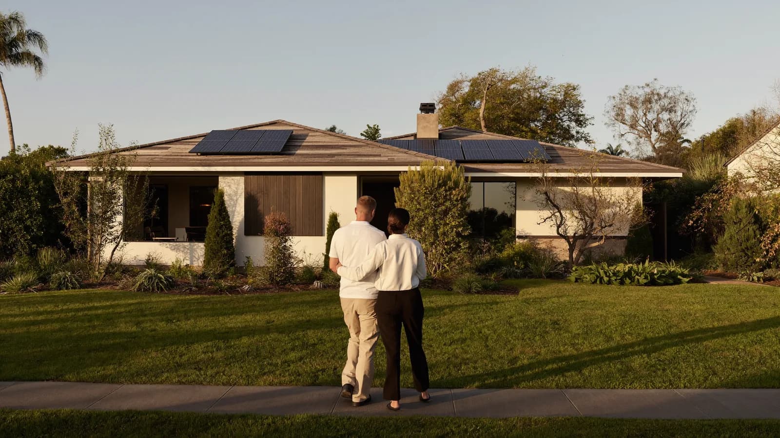 Couple admiring a landscaped home with rooftop solar from the footpath