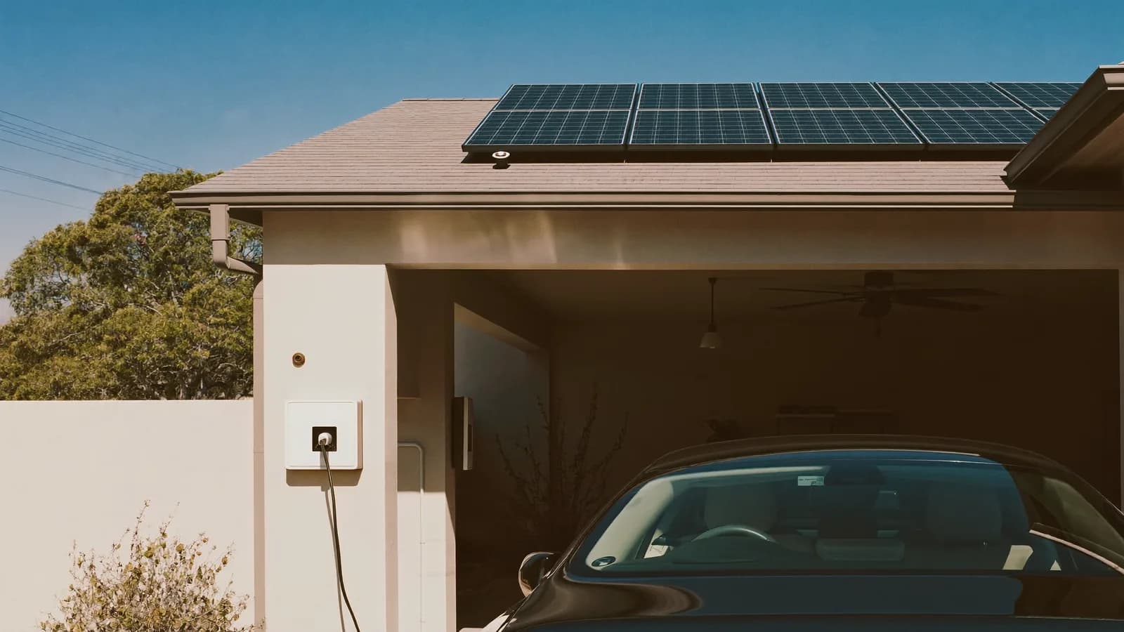 Electric car charging under a solar-panelled carport at midday