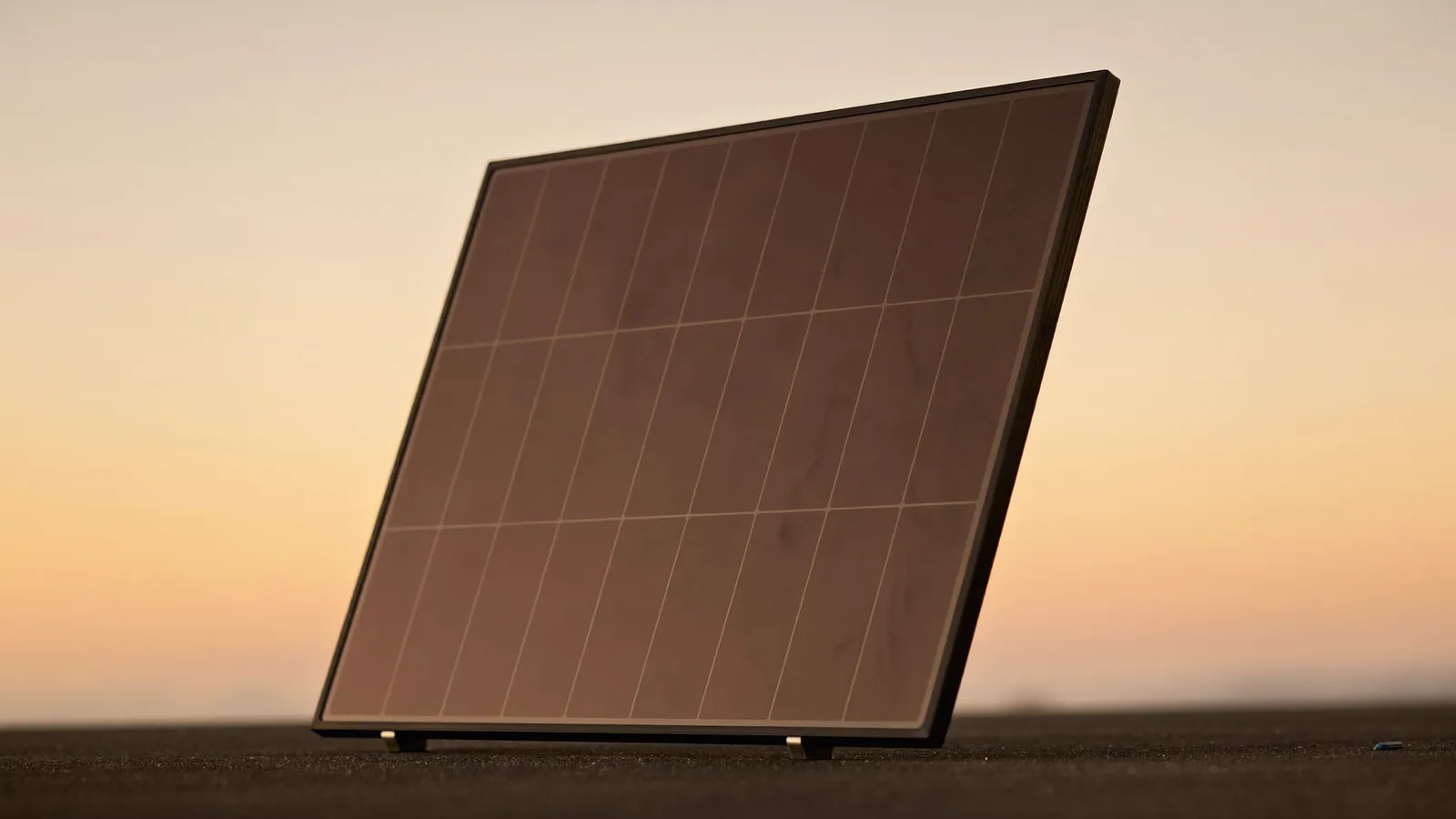 Corner of an all-black solar panel reflecting a dusk sky