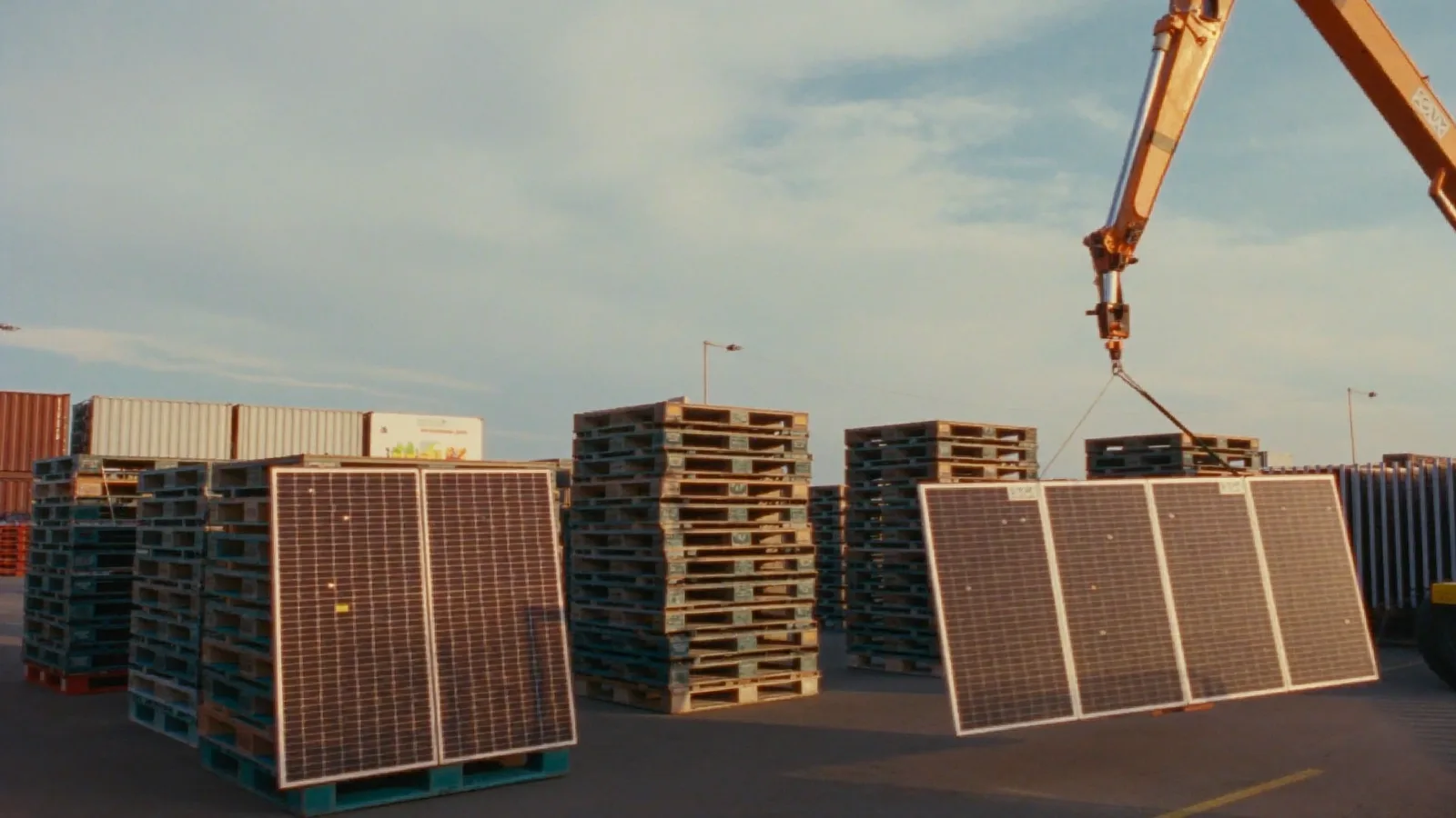 Pallets of solar panels being craned in a logistics yard