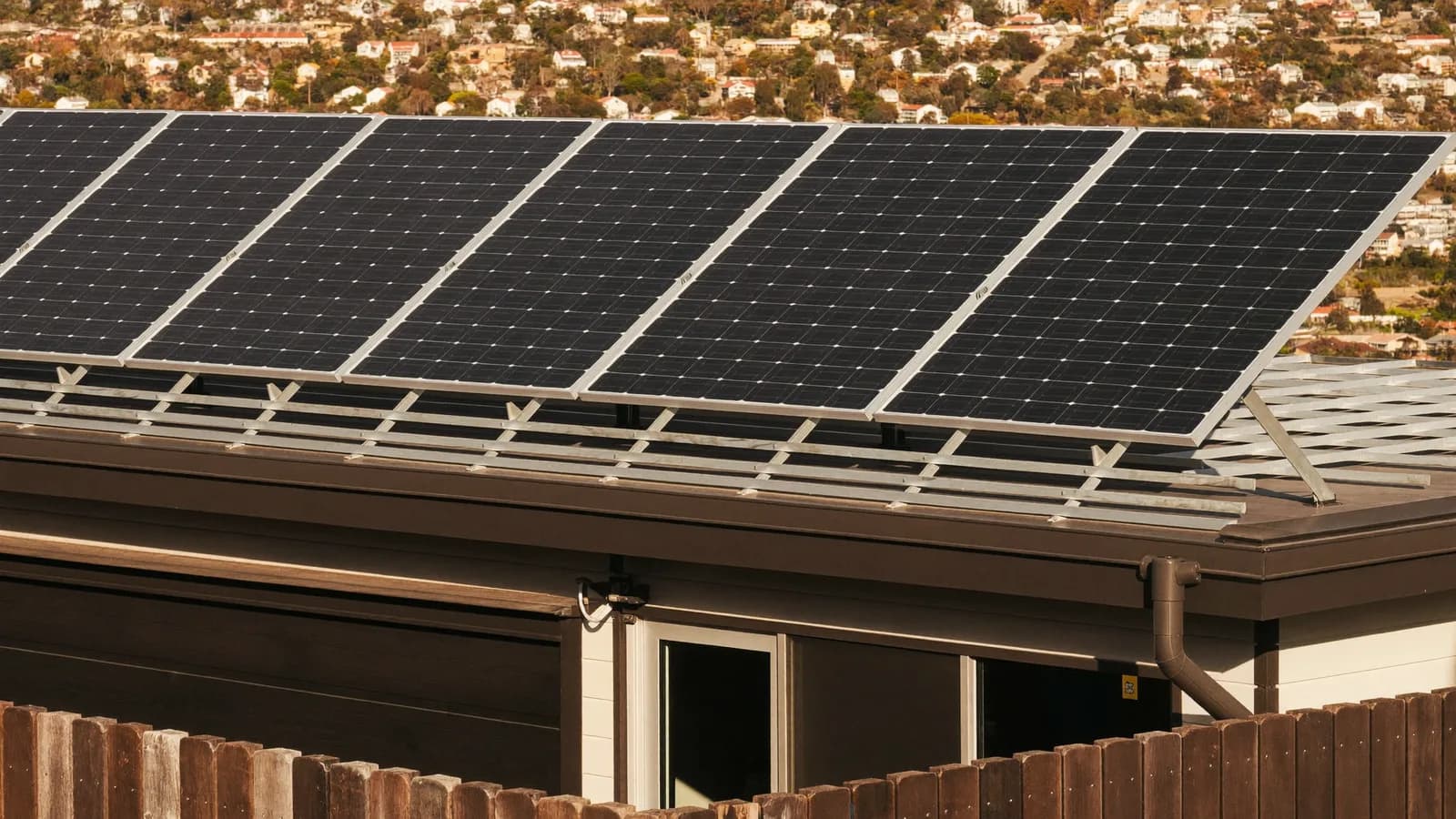 Solar panels on tilted racking across the flat roof of a modern home
