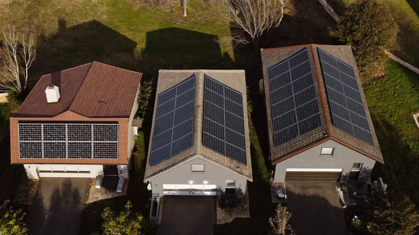 Three neighbouring rooftops with small, medium and large solar arrays