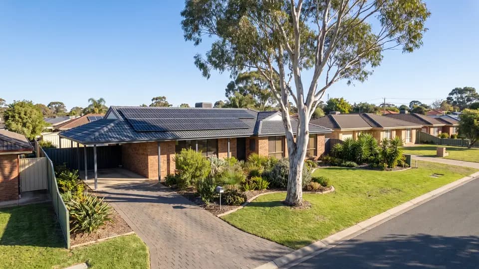Brick house with solar panels on its roof, on a suburban street