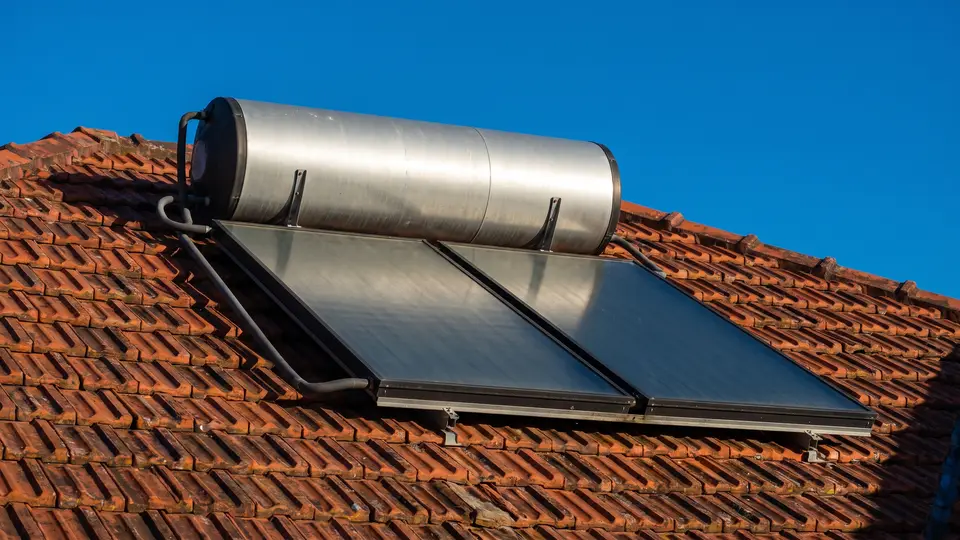 Solar hot water system on a terracotta tile roof: a stainless steel tank mounted above two flat plate collectors